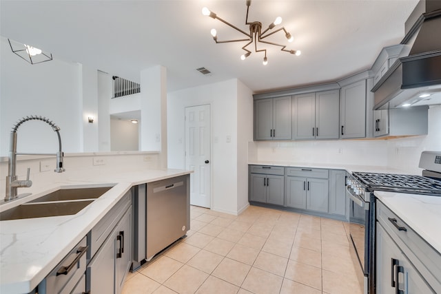 kitchen featuring light stone countertops, sink, an inviting chandelier, and appliances with stainless steel finishes