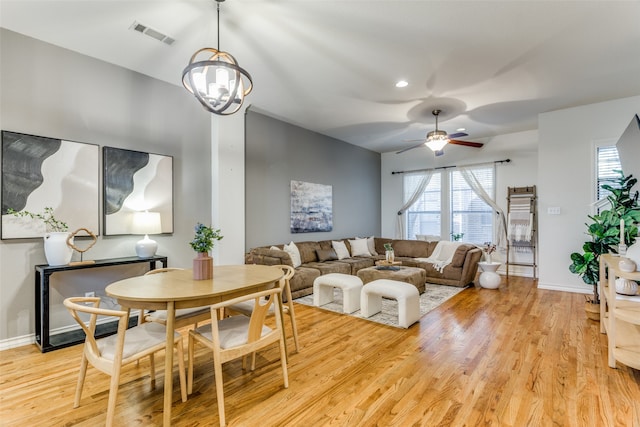 dining space featuring light hardwood / wood-style flooring and ceiling fan with notable chandelier