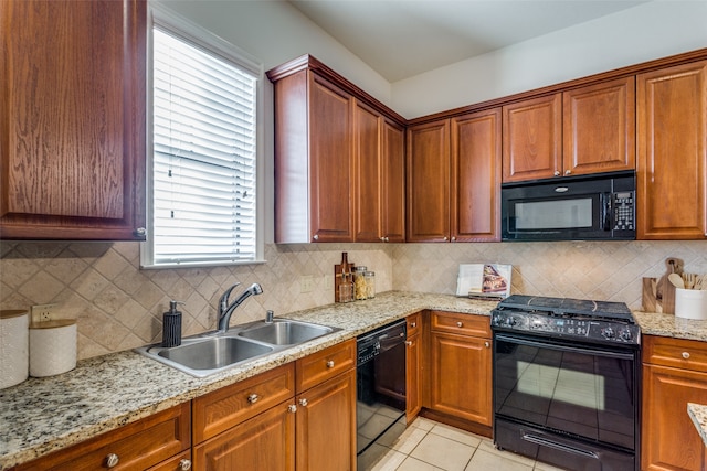 kitchen featuring tasteful backsplash, light tile patterned floors, light stone countertops, black appliances, and sink