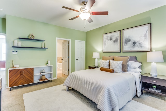 bedroom featuring connected bathroom, light carpet, and ceiling fan