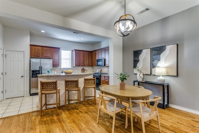 kitchen featuring black appliances, a center island, light hardwood / wood-style floors, and a breakfast bar