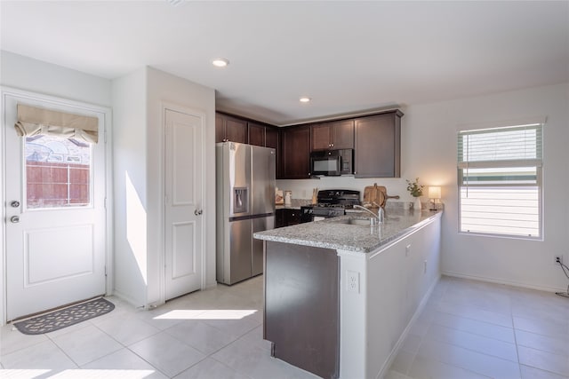 kitchen with kitchen peninsula, dark brown cabinets, black appliances, and a healthy amount of sunlight