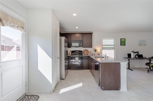 kitchen featuring black appliances, light tile patterned floors, light stone counters, sink, and dark brown cabinets