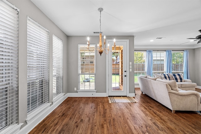 doorway to outside featuring dark wood-type flooring and ceiling fan with notable chandelier