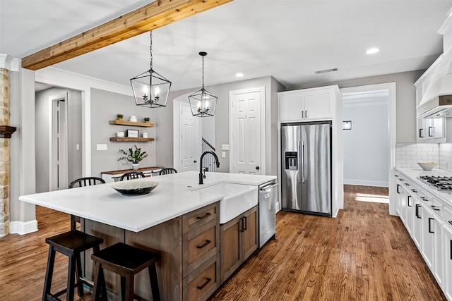 kitchen with stainless steel appliances, dark hardwood / wood-style flooring, white cabinets, sink, and an island with sink