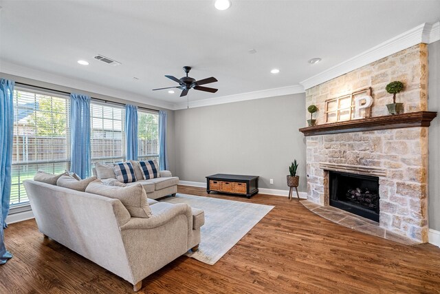 living room featuring dark wood-type flooring, a fireplace, a wealth of natural light, and crown molding