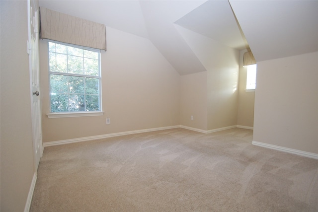 additional living space with vaulted ceiling, a wealth of natural light, and light colored carpet