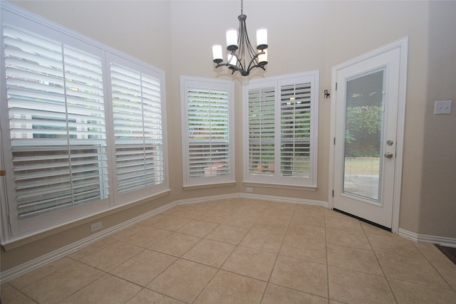 unfurnished dining area featuring light tile patterned flooring, plenty of natural light, and an inviting chandelier