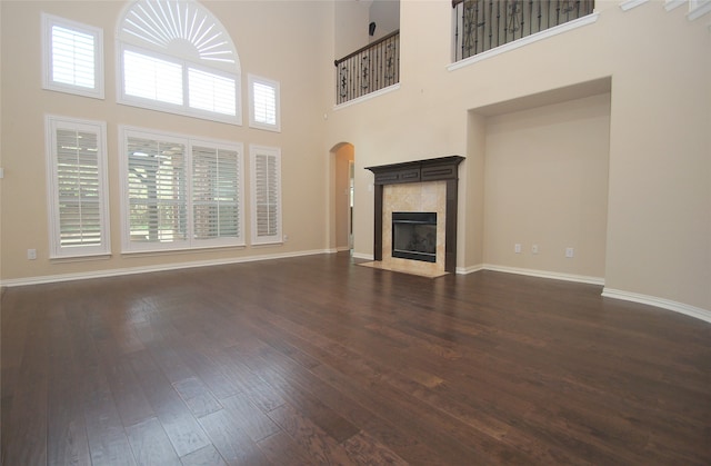 unfurnished living room with a towering ceiling, dark hardwood / wood-style floors, and a healthy amount of sunlight