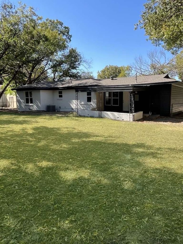 back of property with a yard and central AC unit