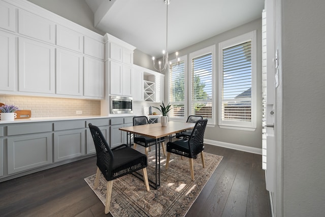 dining room with dark hardwood / wood-style floors, a chandelier, and lofted ceiling