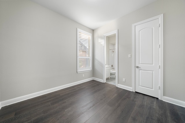 unfurnished bedroom with dark wood-type flooring and ensuite bathroom