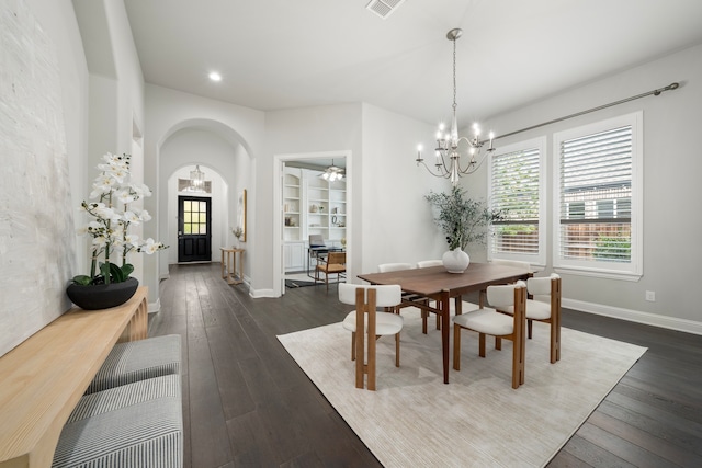 dining area featuring built in features, dark hardwood / wood-style floors, and a chandelier