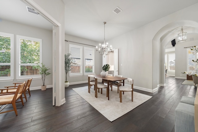 dining space with dark wood-type flooring and a notable chandelier