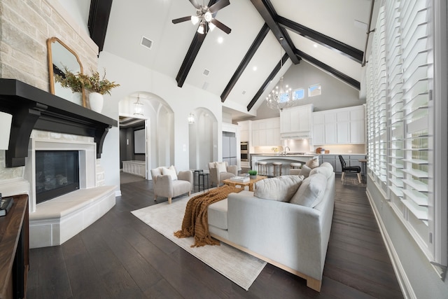 living room featuring high vaulted ceiling, dark wood-type flooring, ceiling fan with notable chandelier, and beam ceiling