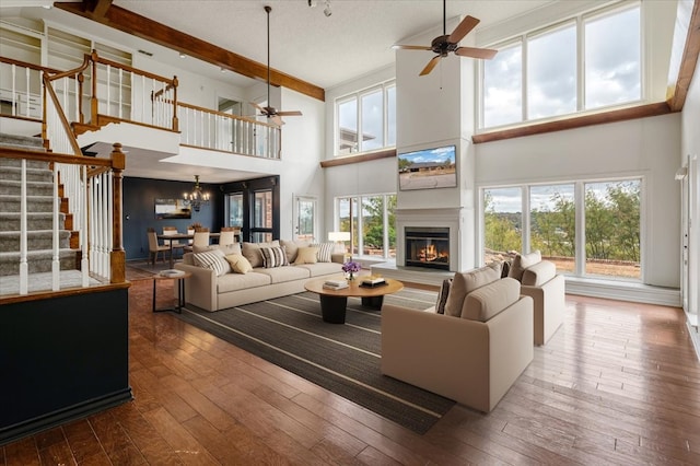 living room with beamed ceiling, dark wood-type flooring, ceiling fan with notable chandelier, and high vaulted ceiling