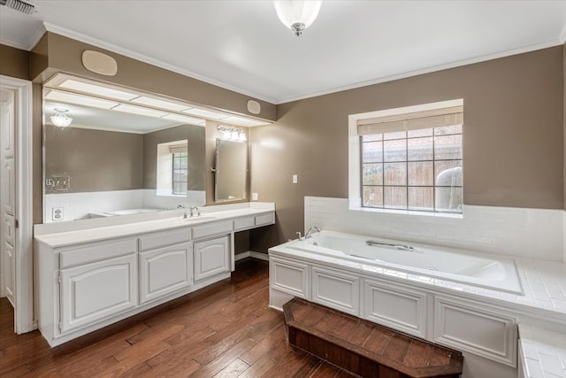 bathroom with a bathing tub, hardwood / wood-style floors, vanity, and ornamental molding