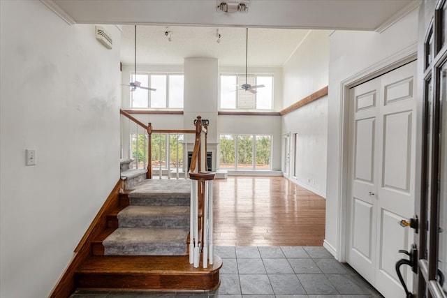 staircase featuring hardwood / wood-style floors, crown molding, a towering ceiling, and ceiling fan