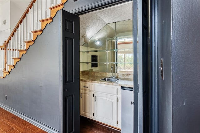 bar with sink, dishwasher, lofted ceiling, white cabinets, and dark wood-type flooring