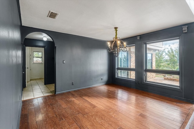 unfurnished dining area with ornamental molding, a chandelier, hardwood / wood-style flooring, and a textured ceiling