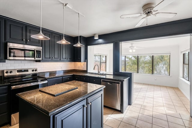 kitchen featuring tasteful backsplash, sink, a center island, stainless steel appliances, and dark stone countertops