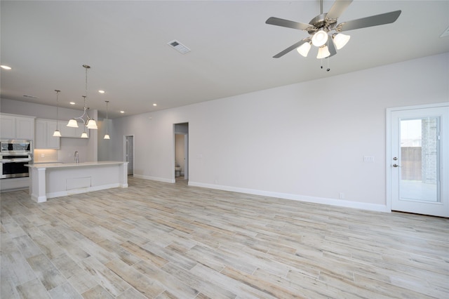 unfurnished living room featuring ceiling fan, light hardwood / wood-style floors, and sink