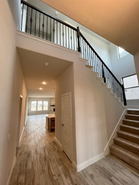 stairs with hardwood / wood-style flooring and a towering ceiling