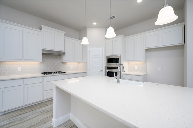 kitchen with sink, backsplash, decorative light fixtures, white cabinets, and appliances with stainless steel finishes