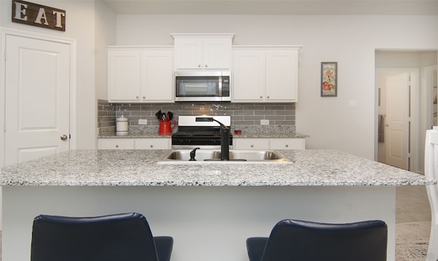 kitchen with sink, white cabinetry, a breakfast bar area, and a center island with sink