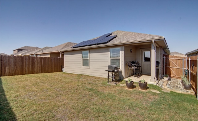 rear view of house featuring solar panels and a yard