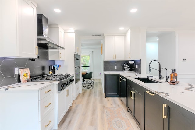 kitchen featuring sink, white cabinetry, wall chimney range hood, and light wood-type flooring