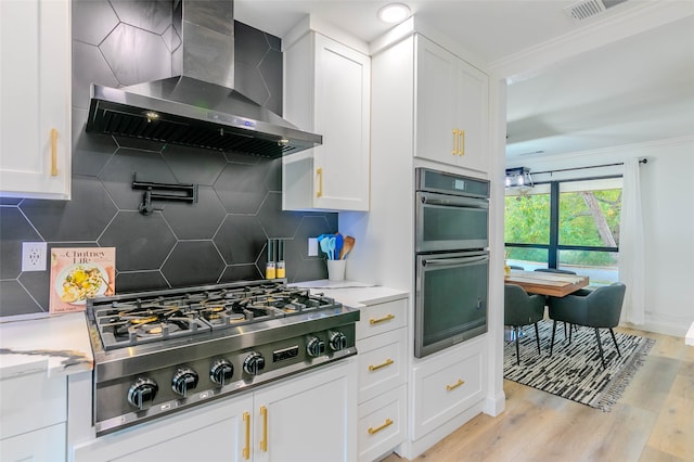 kitchen with white cabinetry, backsplash, wall chimney range hood, and appliances with stainless steel finishes