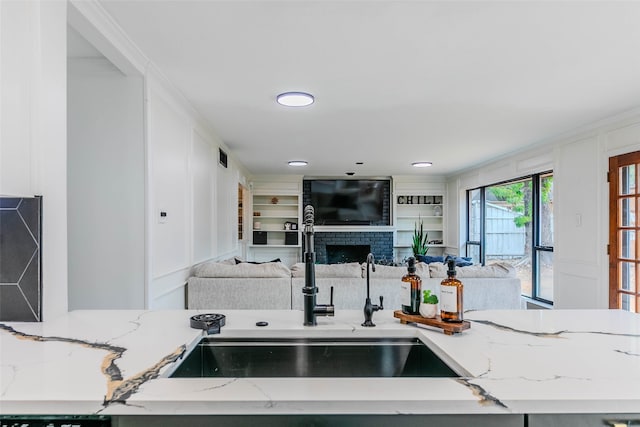 kitchen with light stone countertops, sink, and a fireplace