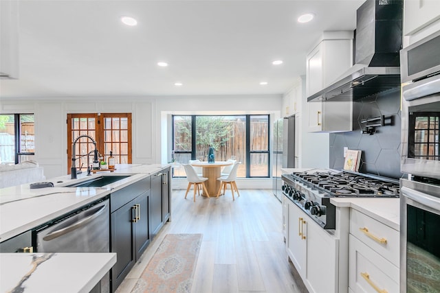 kitchen with white cabinetry, wall chimney range hood, stainless steel appliances, and plenty of natural light