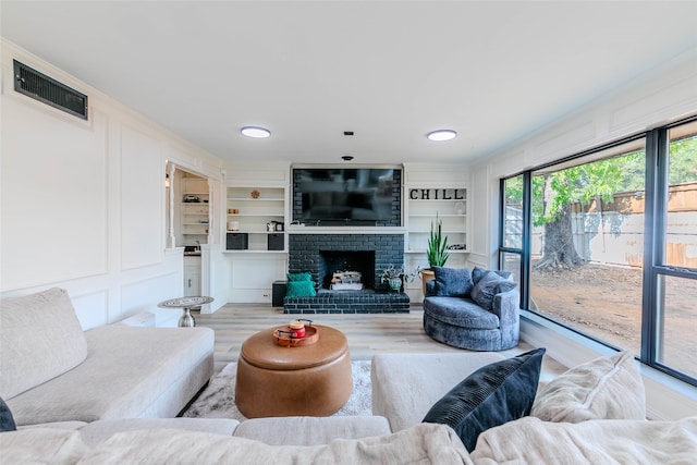 living room with built in features, light hardwood / wood-style flooring, and a fireplace