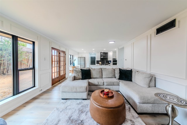 living room featuring french doors, ornamental molding, and light hardwood / wood-style flooring