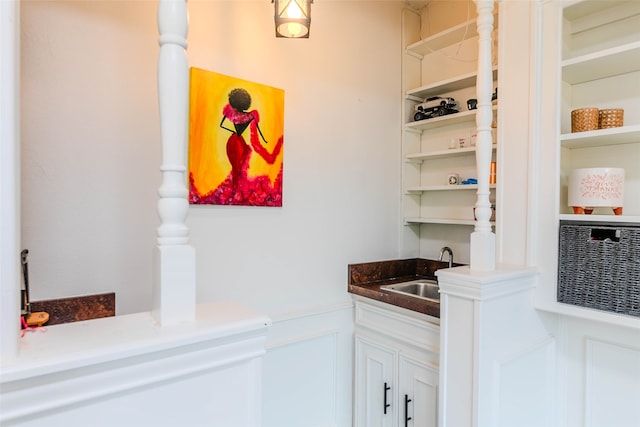 bar with white cabinetry and sink