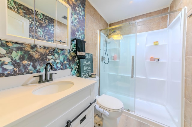 bathroom featuring vanity, a shower with shower door, toilet, and tile walls