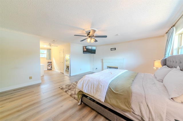 bedroom featuring crown molding, a textured ceiling, light wood-type flooring, and ceiling fan