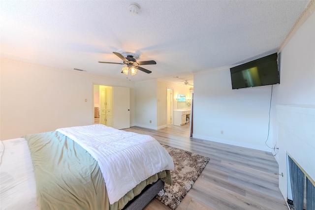 bedroom with light wood-type flooring, ensuite bath, a textured ceiling, ceiling fan, and ornamental molding