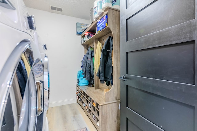 walk in closet with washer and dryer and light hardwood / wood-style floors