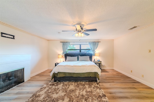 bedroom featuring ceiling fan, ornamental molding, and light hardwood / wood-style flooring