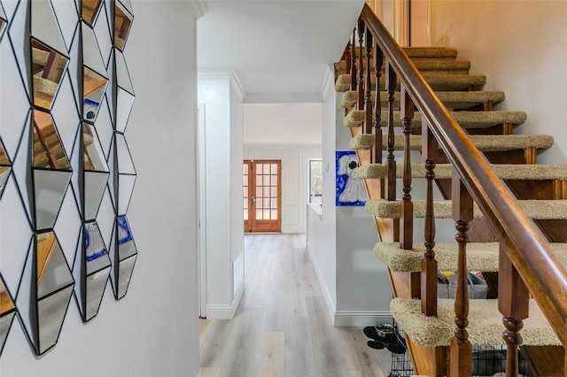 stairs with french doors, hardwood / wood-style flooring, and ornamental molding