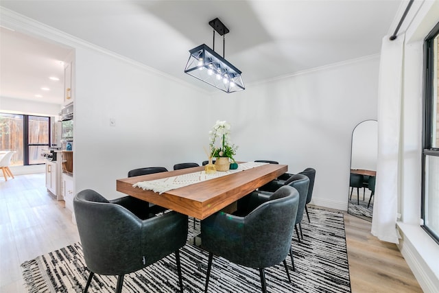 dining room with ornamental molding and light wood-type flooring