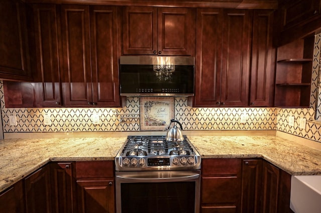 kitchen featuring ventilation hood, light stone countertops, high end stainless steel range, and tasteful backsplash