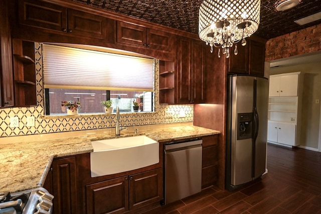 kitchen with sink, dark wood-type flooring, stainless steel appliances, an inviting chandelier, and light stone counters