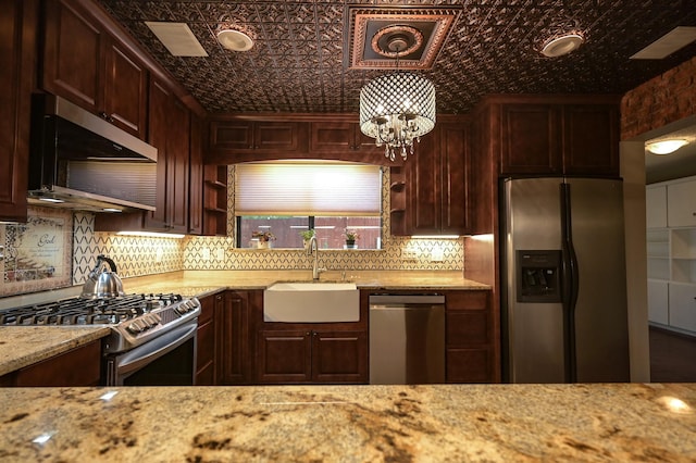 kitchen featuring light stone countertops, sink, hanging light fixtures, stainless steel appliances, and a chandelier