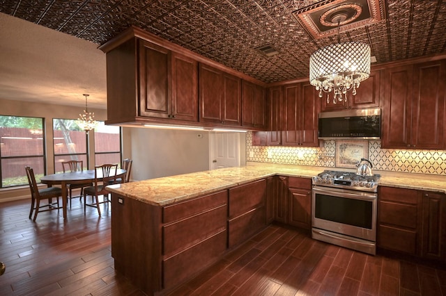 kitchen featuring kitchen peninsula, dark hardwood / wood-style flooring, stainless steel appliances, an inviting chandelier, and hanging light fixtures