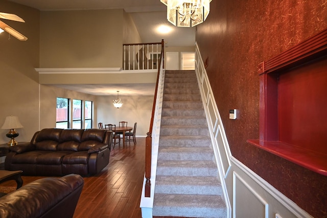 stairs with a chandelier, hardwood / wood-style floors, and a towering ceiling