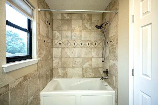 bathroom featuring a textured ceiling and tiled shower / bath combo